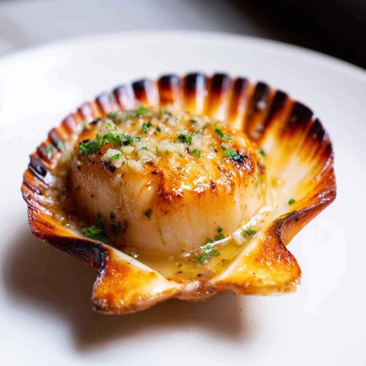 A close-up of pan-seared scallops with vibrant lemon-garlic butter sauce and a wedge on the side.