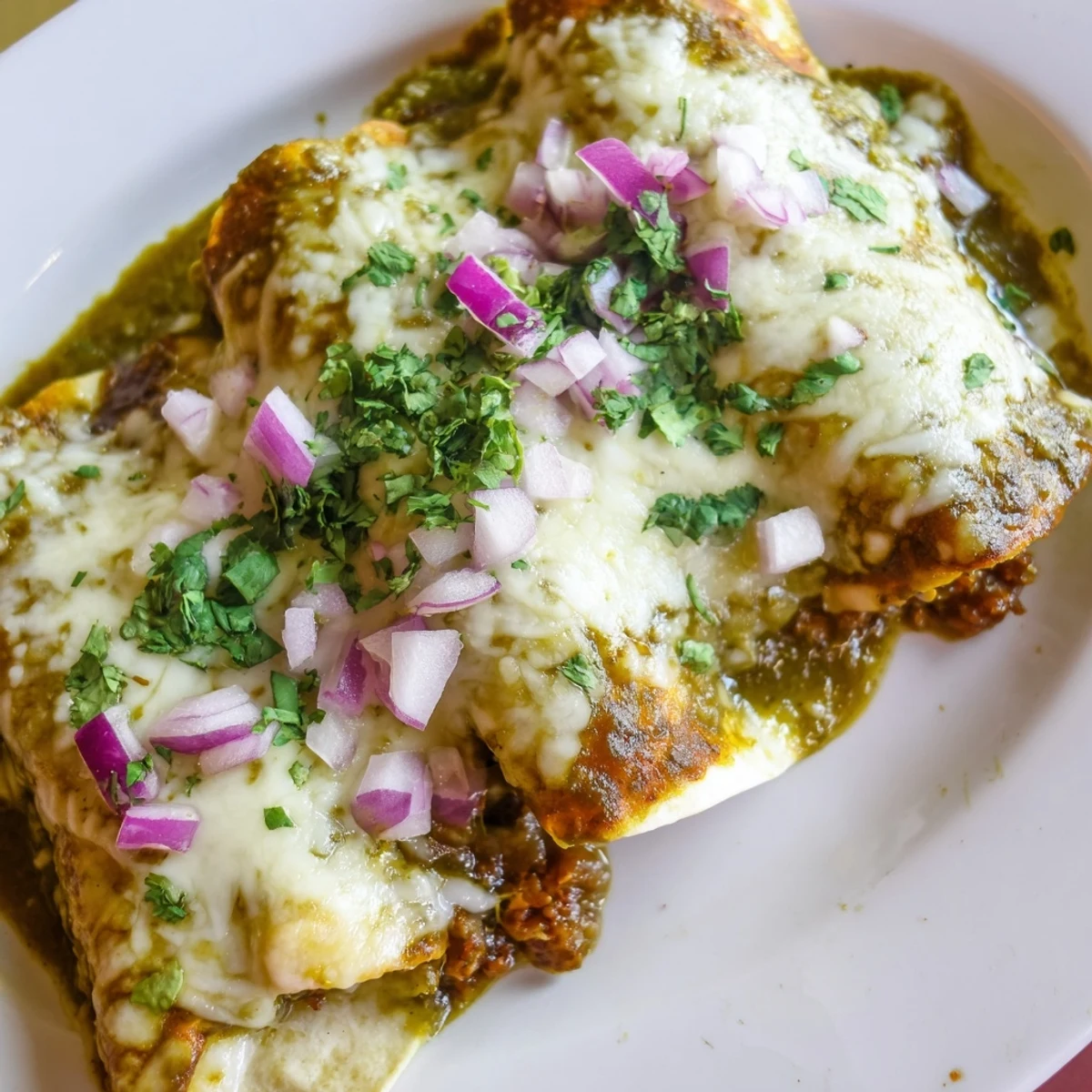 Golden-brown Beef Enchiladas with Green Chili Sauce, bubbling with melted Monterey Jack cheese and ready to serve.