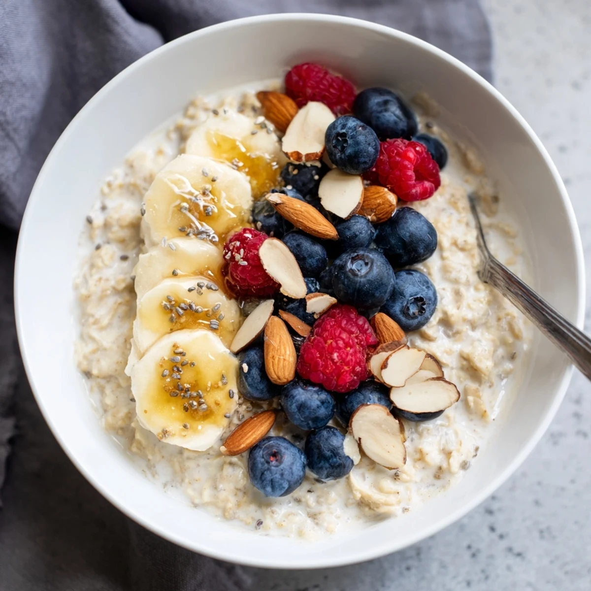 Steam rises from this Creamy Breakfast Oats bowl, featuring chopped nuts and chia seeds for a wholesome, satisfying breakfast.