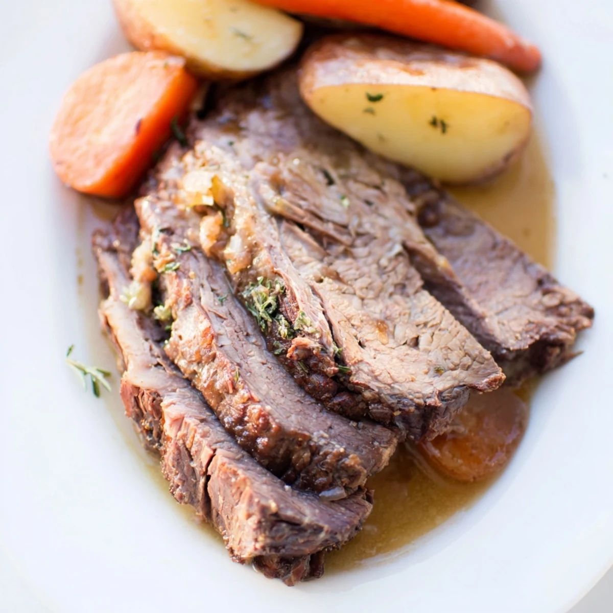 Freshly roasted Beef Supper Roast with carrots and potatoes served family-style on a platter.