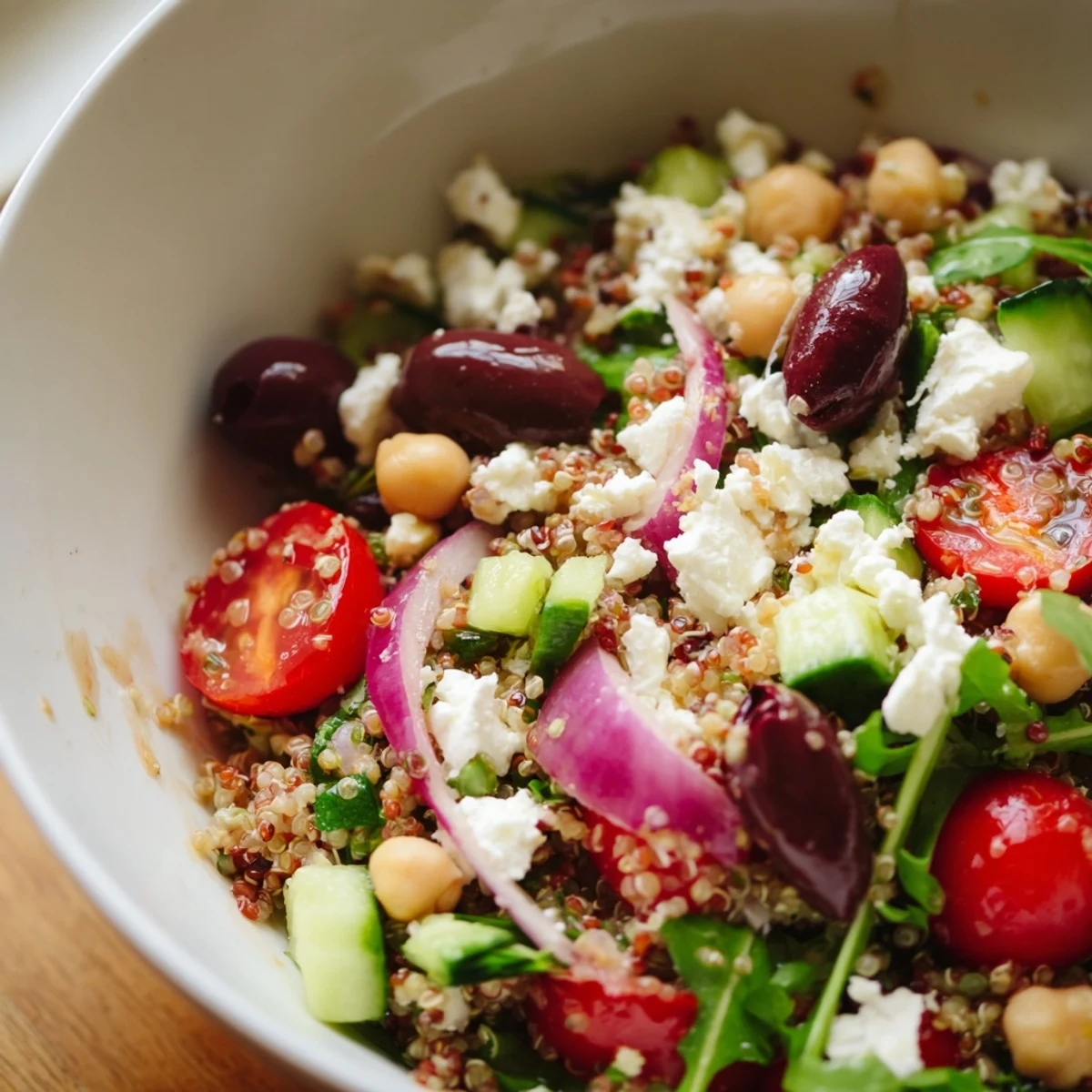 Mediterranean Supper Salad with chickpeas, feta, and Kalamata olives in a white bowl, drizzled with tangy dressing.