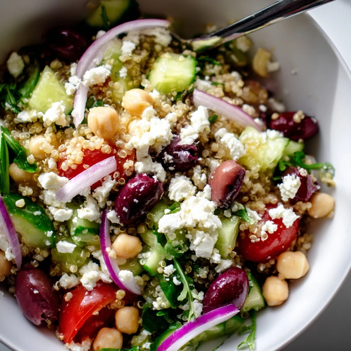 Close-up of Mediterranean Supper Salad showing crumbled feta, red onion, and bell pepper on a rustic table setting.