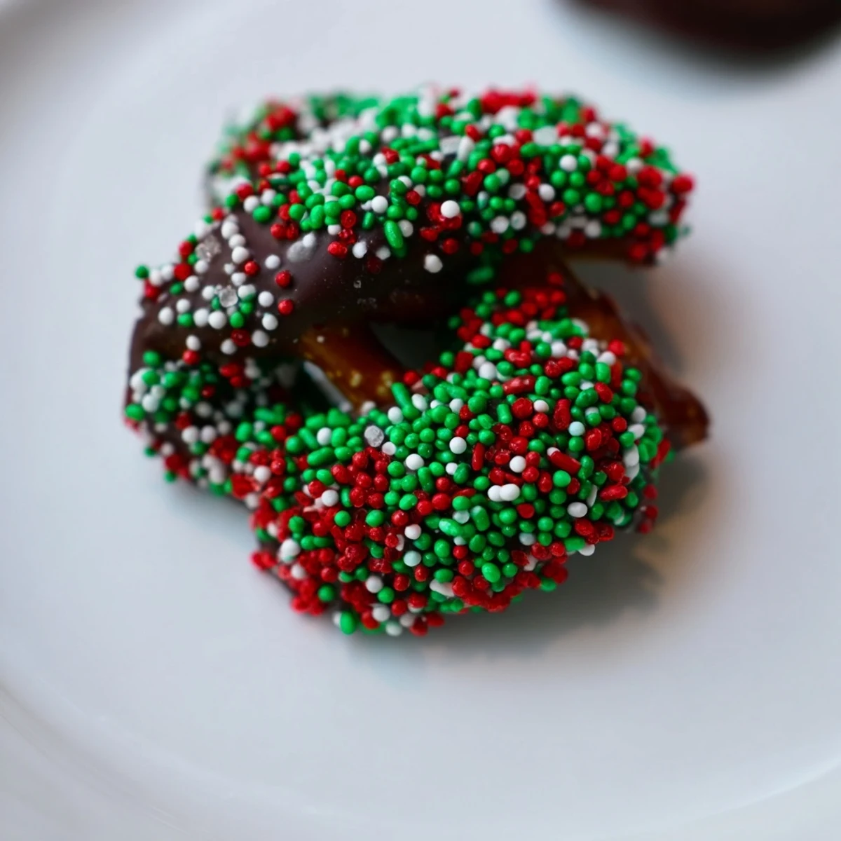 Crunchy pretzels half-dipped in rich melted chocolate and sprinkled with red and green festive toppings.