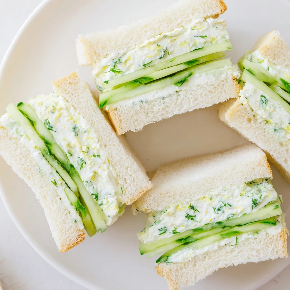 Stack of vibrant Green Cucumber Sandwiches with Herb Cheese, featuring crunchy cucumber slices and fresh dill garnish.