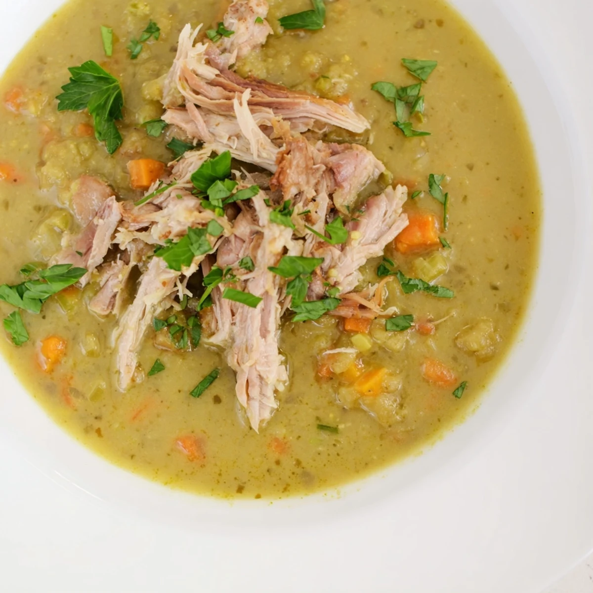 Close-up of Green Split Pea Soup with Smoked Turkey Leg, highlighting creamy peas and shredded meat in a rich, smoky broth.