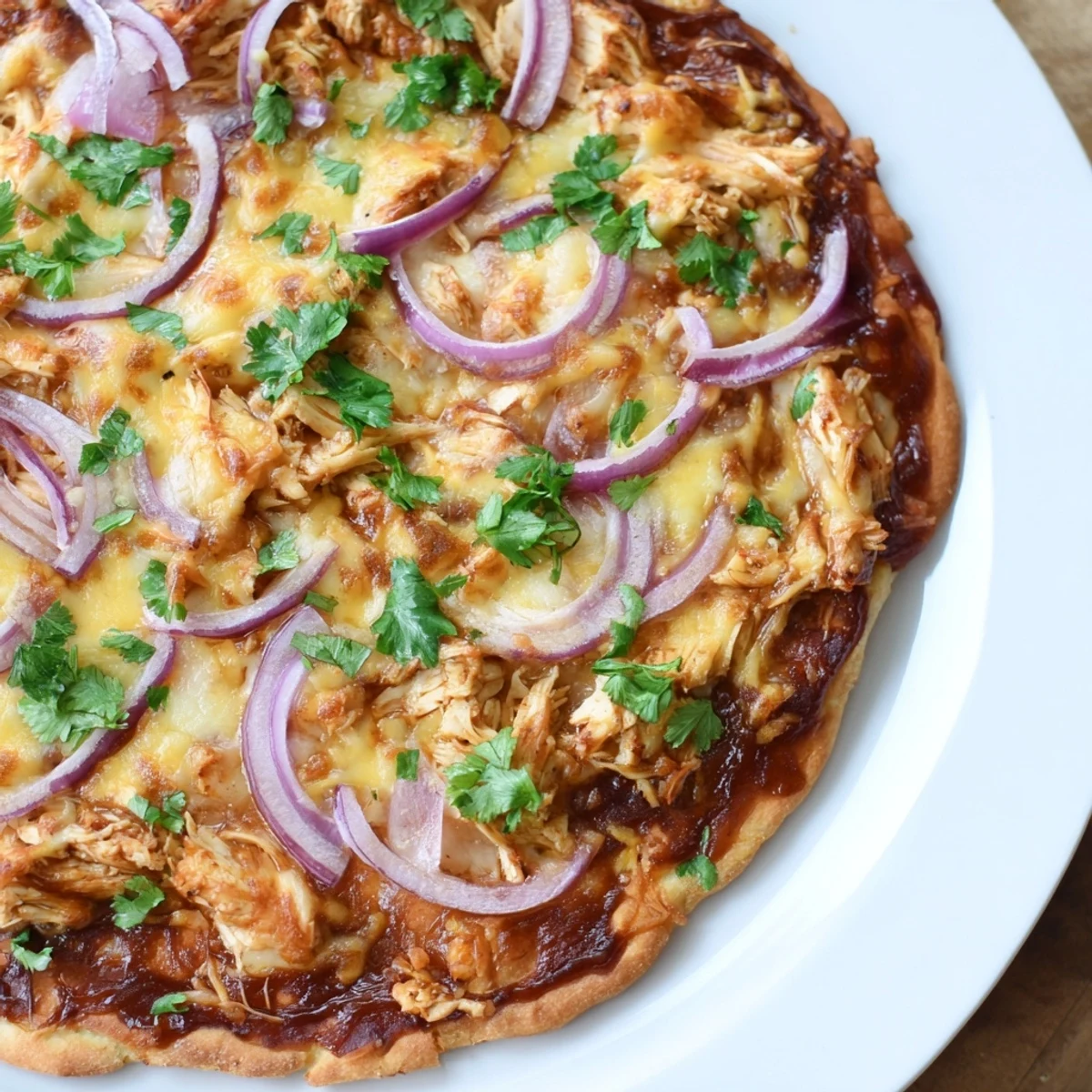 A close-up slice of BBQ Chicken Pizza with Red Onion and Cilantro, showcasing melty cheese and tender chicken on a golden crust.