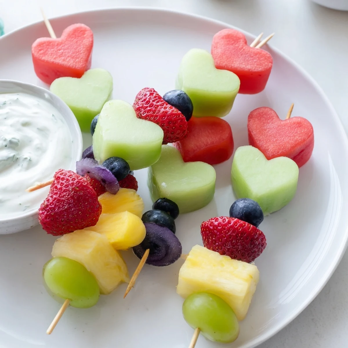 Vibrant Sweetheart Fruit Skewers with Yogurt Dip served for a party, showcasing blueberries, cantaloupe hearts, and elegant presentation.