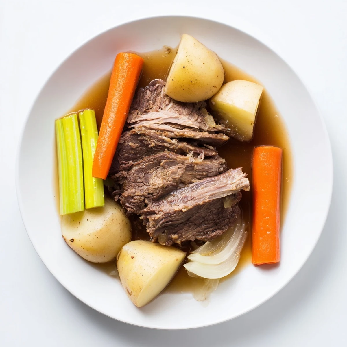 A slice of Slow Cooker Beef Pot Roast with Root Vegetables rests on a white plate, revealing tender beef and glazed carrots.