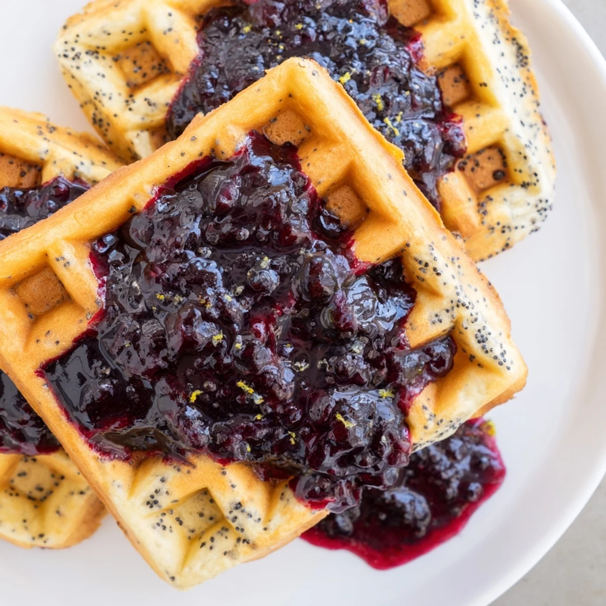 Golden brown Lemon Poppy Seed Waffles topped with a warm blueberry syrup pool, steam rising to highlight the sweet and tangy breakfast aromas on a rustic plate.