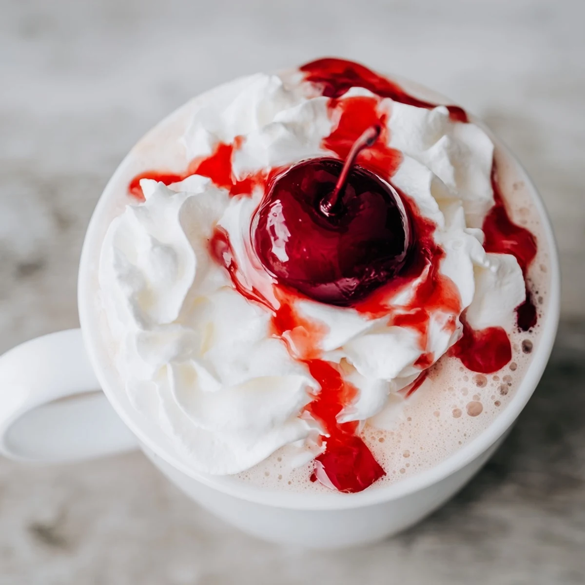 A steaming mug of Viral Cherry Vanilla Latte with glossy cherry syrup drizzle on foam. 