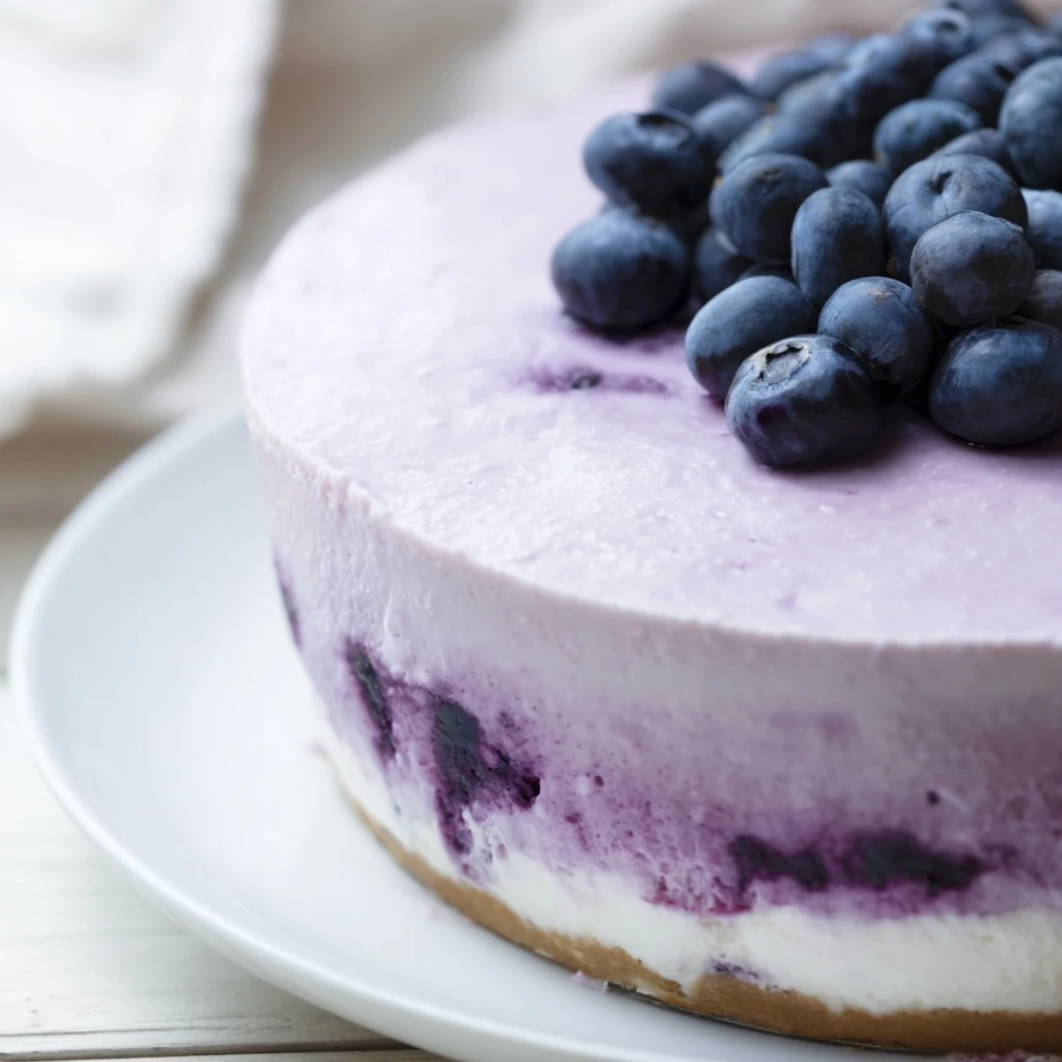 A slice of Blueberry Mousse Cheesecake with a creamy filling and a blueberry mousse swirl, topped with fresh berries.