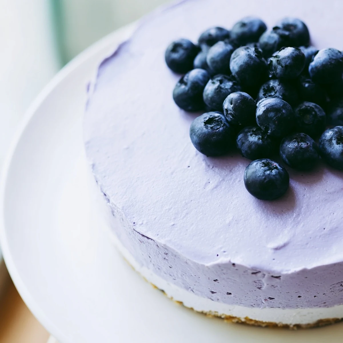 Close up view of Blueberry Mousse Cheesecake dessert showing a creamy texture and glossy blueberry mousse on a serving plate.
