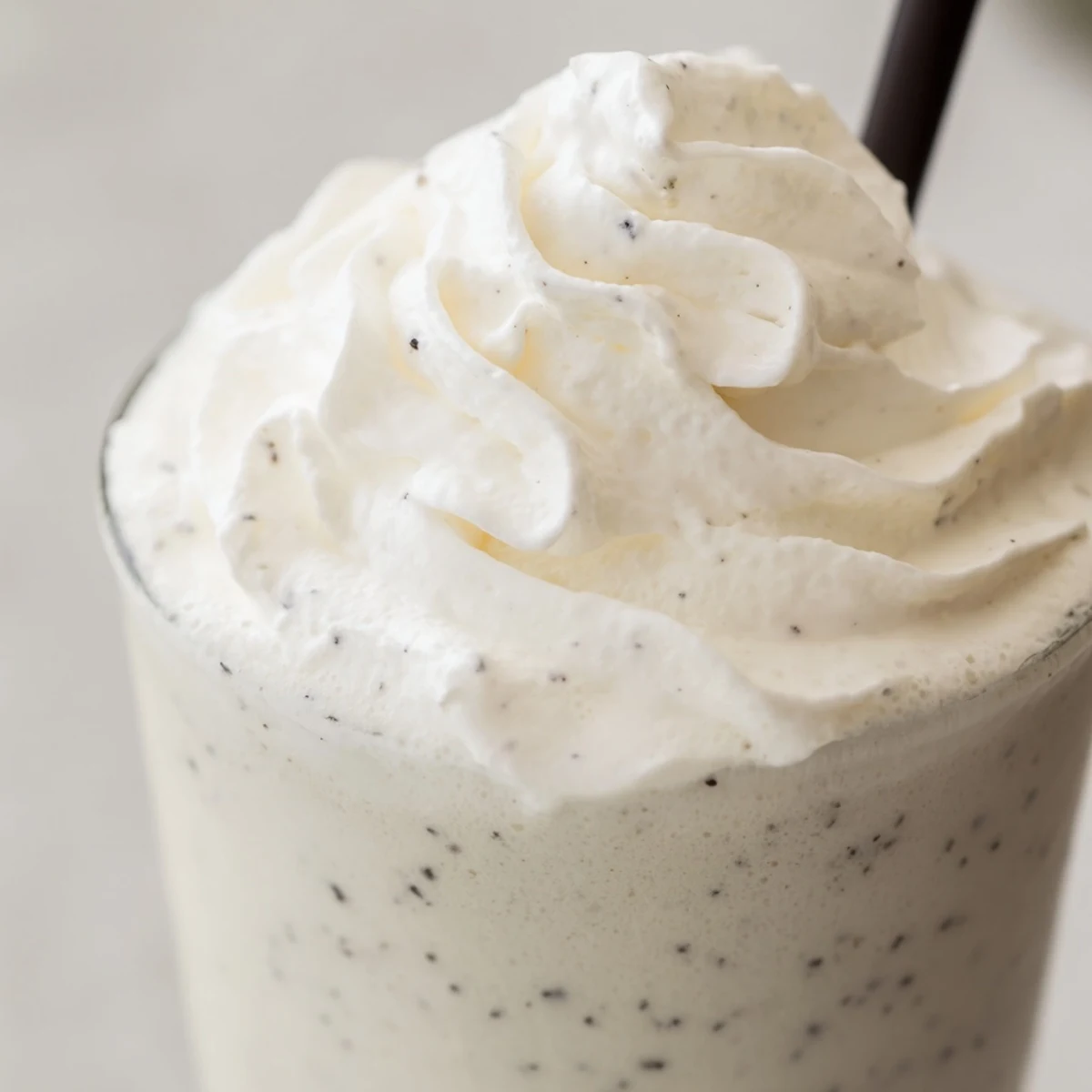 A close-up of a Vanilla Bean Frappuccino topped with whipped cream in a tall glass.