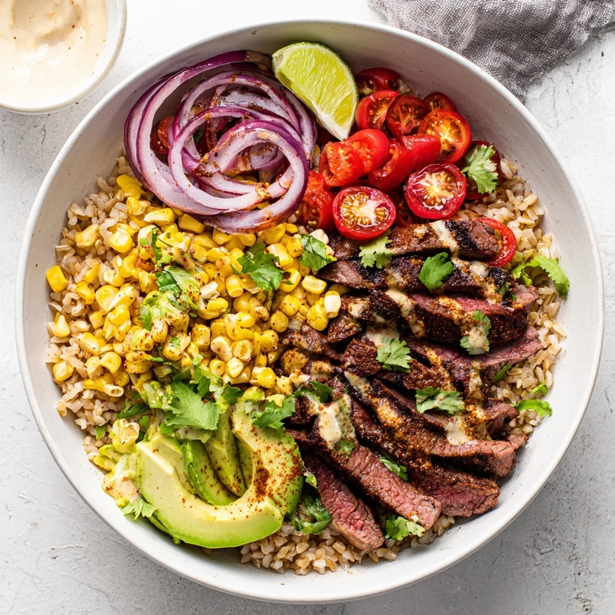 Juicy grilled steak slices fanning out over brown rice in a vibrant Steak Avocado Roasted Corn Bowl, topped with creamy avocado and sweet charred corn.