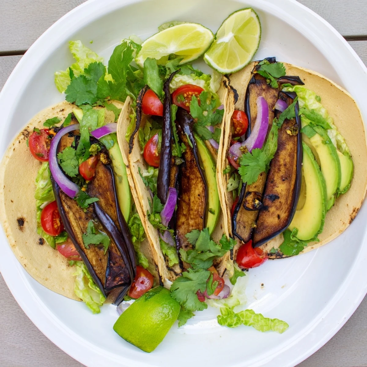 Grilled Charred Eggplant Tacos with smoky slices and fresh lime wedges on warm corn tortillas.