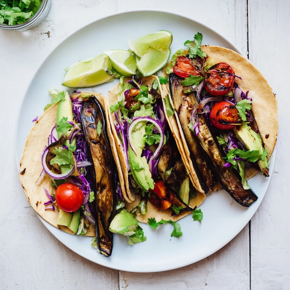 Sizzling Charred Eggplant Tacos on a plate with cilantro garnish and vibrant red onions.
