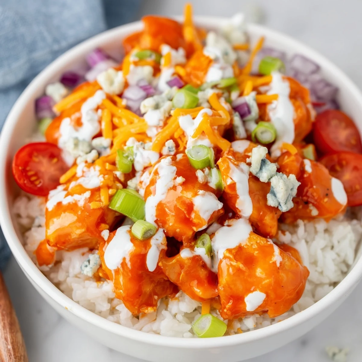 Spicy Buffalo chicken pieces glisten over fluffy white rice, topped with cool creamy ranch, shredded cheddar, and crisp romaine.