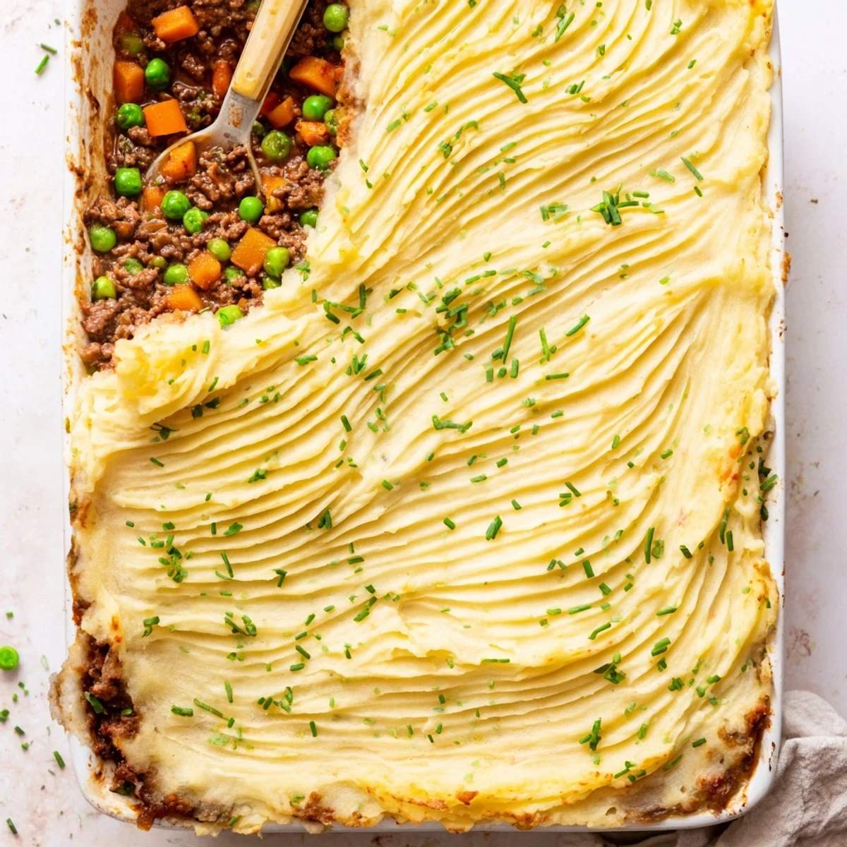 Golden-brown creamy garlic mashed potatoes top a savory ground lamb filling with peas and carrots in this hearty Shepherds Pie with Creamy Garlic Mashed Potatoes.
