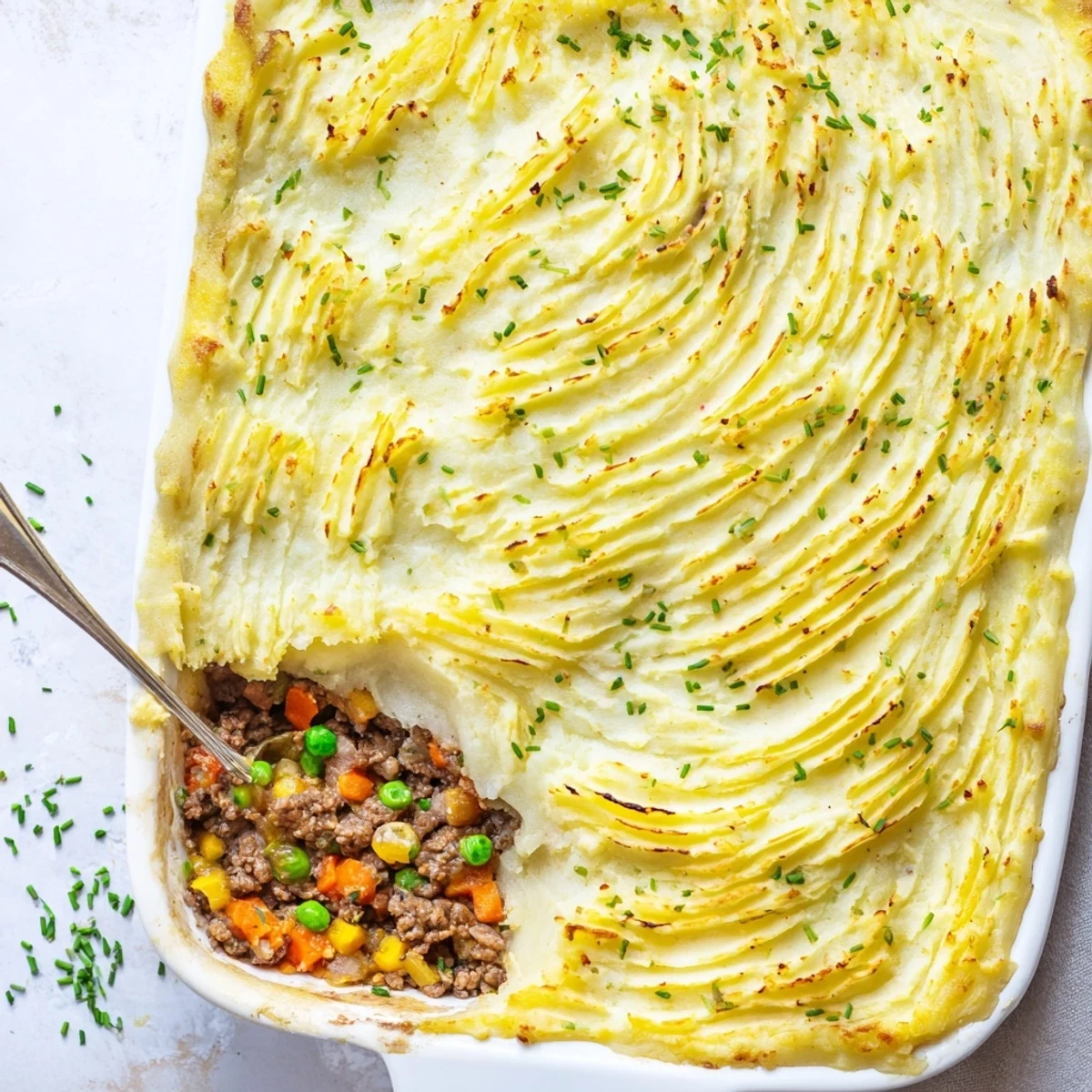 A close-up of Shepherds Pie with Creamy Garlic Mashed Potatoes highlights crisp potato peaks and a bubbling beef and pea filling, perfect for family dinners.