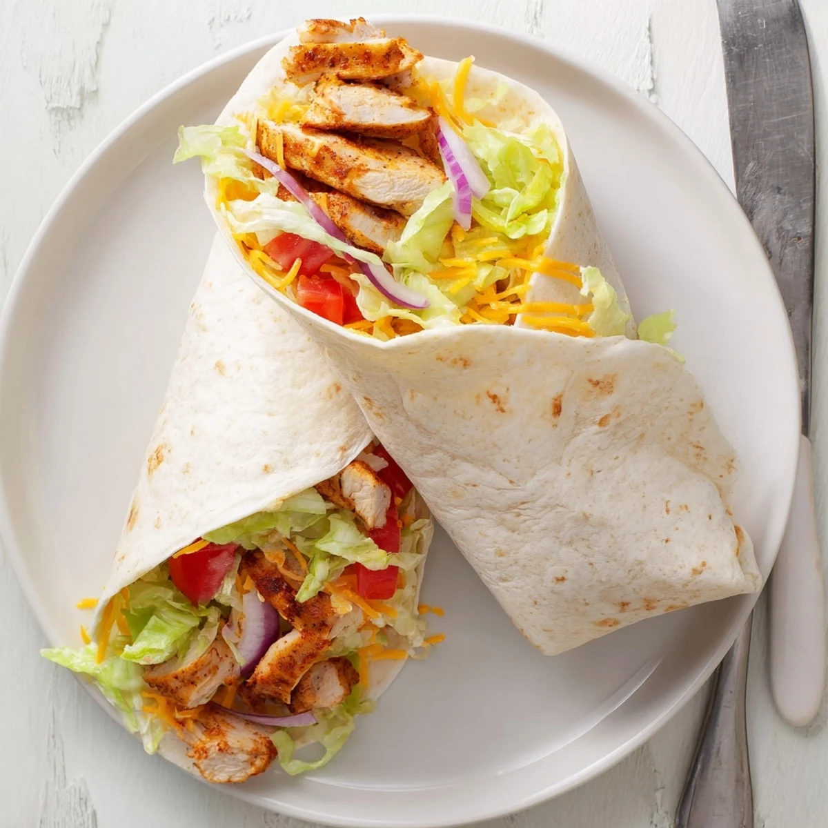 Delicious homemade cheesy garlic chicken wraps wrapped tightly with juicy chicken and shredded cheddar cheese ready to serve