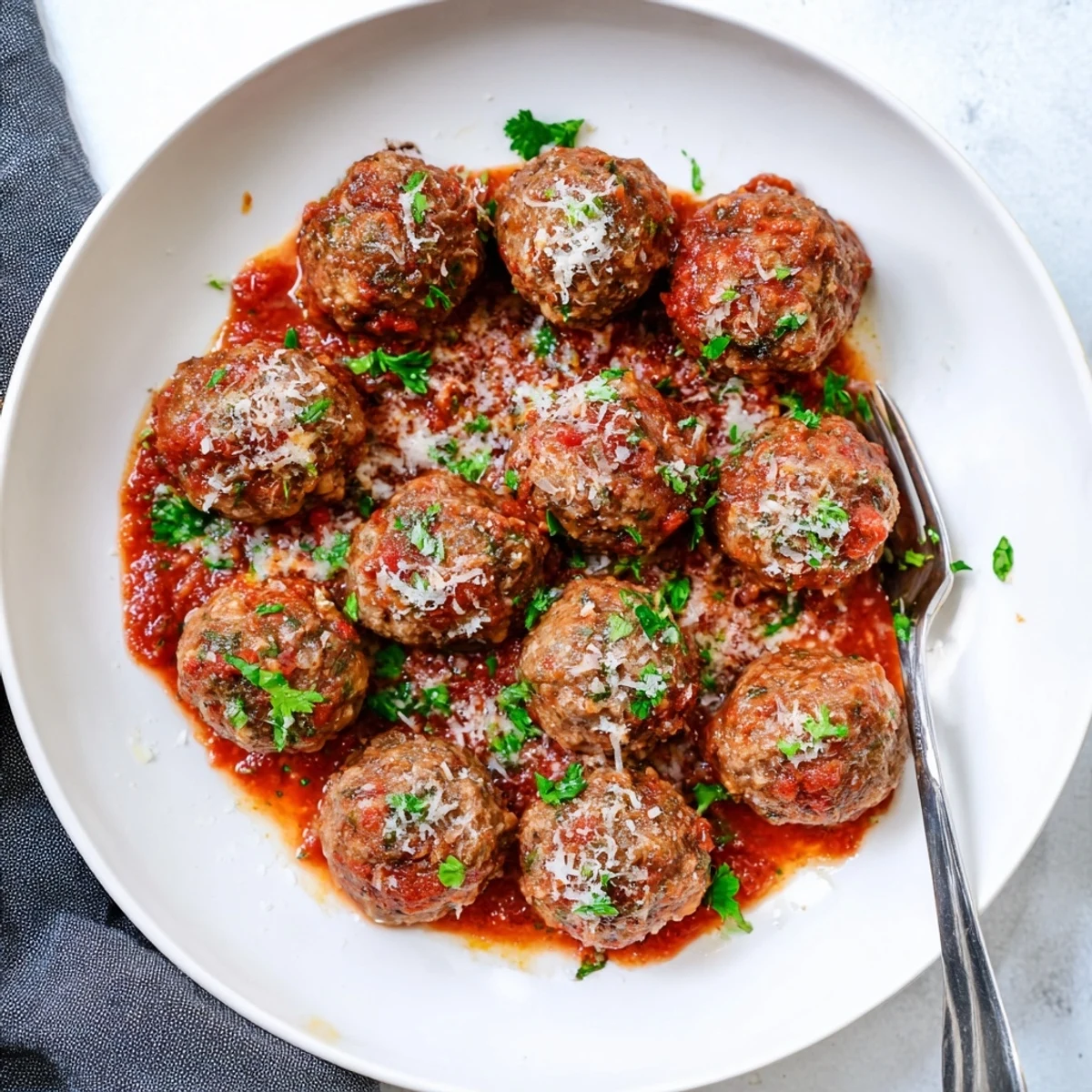 Tender authentic Italian meatballs simmered in rich tomato sauce, garnished with fresh Parmesan