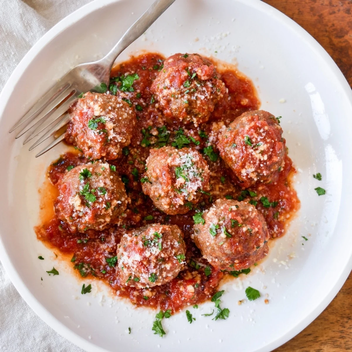 Golden brown authentic Italian meatballs served over spaghetti with fresh parsley and grated cheese