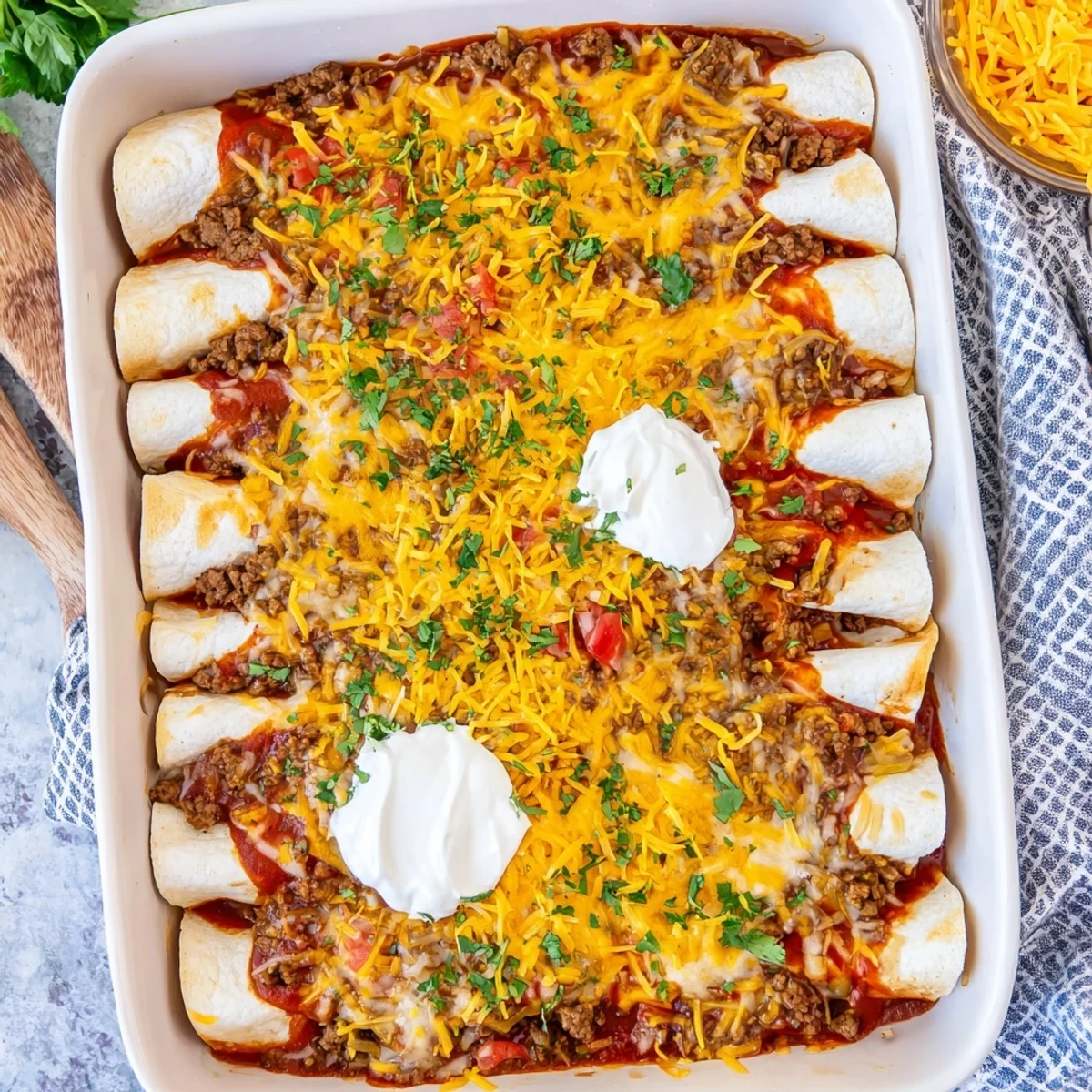 Baked savory beef enchiladas smothered in red sauce and bubbling melted cheddar cheese