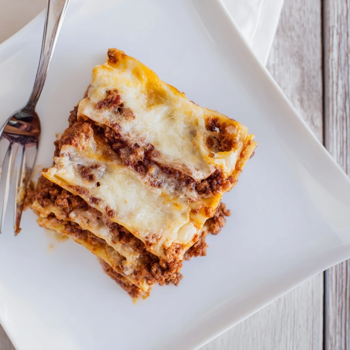 Hearty classic lasagna showing distinct pasta layers with creamy béchamel and melted mozzarella topping