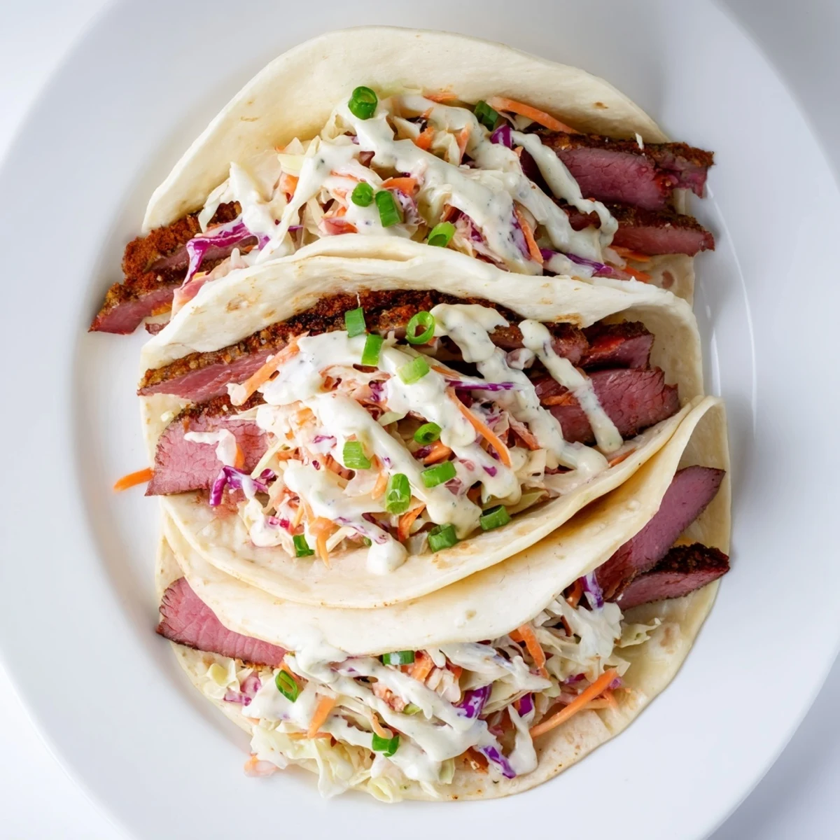 Homemade Irish tacos loaded with savory sliced corned beef topped with colorful vegetable slaw and zesty cream