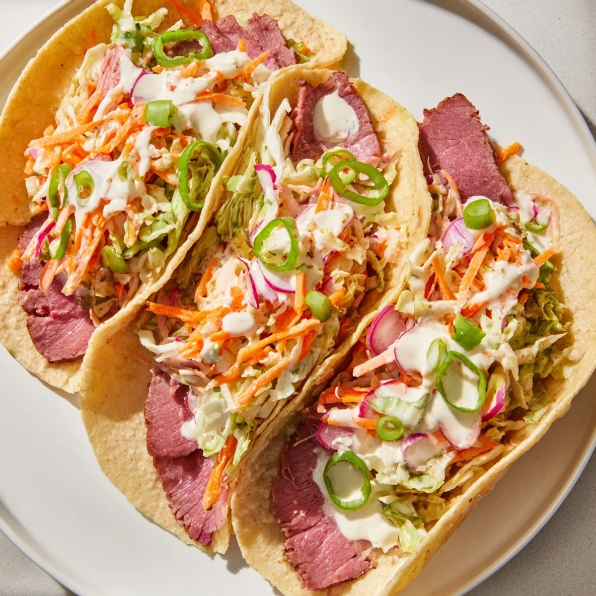 Warm tortilla wraps stuffed with spiced corned beef crunchy cabbage carrot slaw and smooth horseradish sour cream