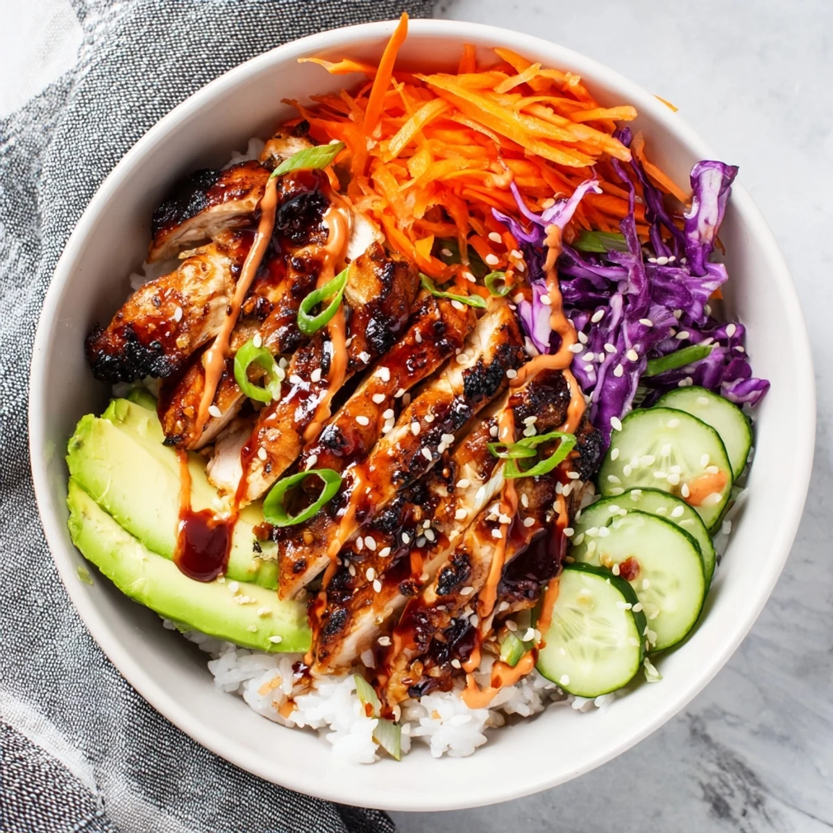 Savory Korean BBQ chicken thighs served over rice with fresh purple cabbage, cucumber, and creamy spicy sauce