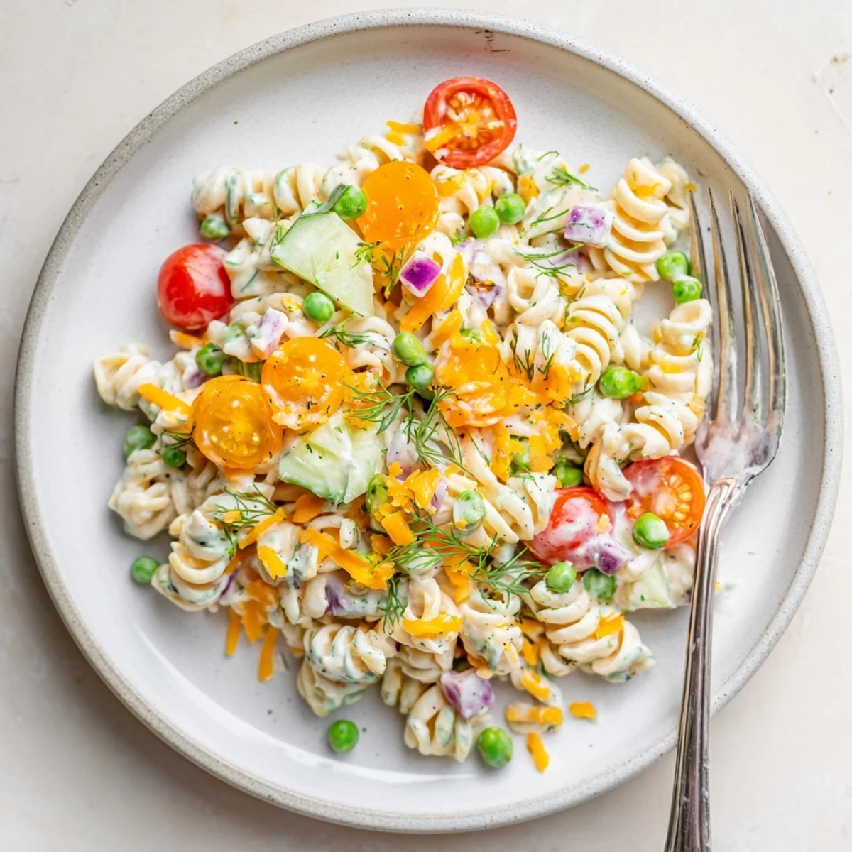 Chilled creamy ranch pasta salad featuring rotini tomatoes and cucumber in white bowl