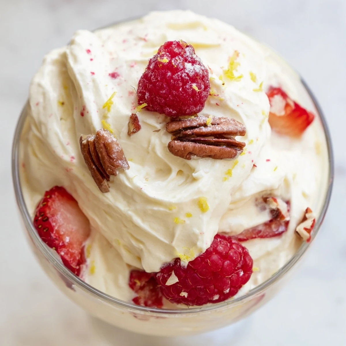 Creamy keto cheesecake fluff piled in glasses topped with fresh red raspberries