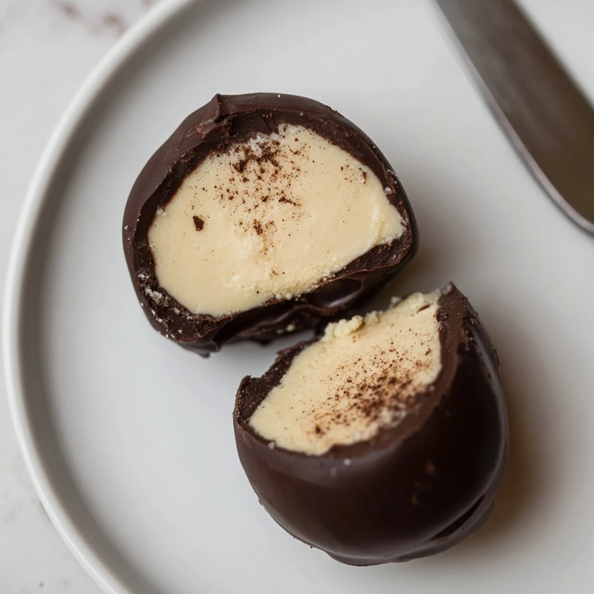 Dark Chocolate Eggnog Truffles arranged on parchment, glossy shells dusted with nutmeg