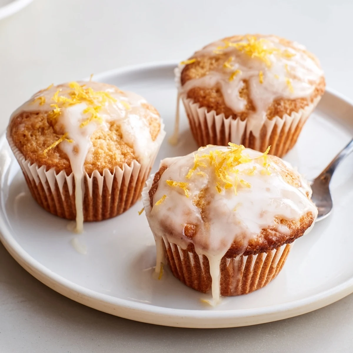 Warm Glazed Lemon Ginger Muffins drizzled with tangy glaze, served with tea