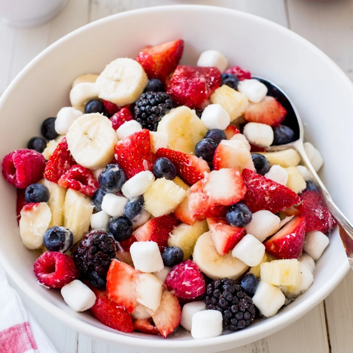 Chilled Red White And Blue Fruit Salad tossed with honey, pineapple, and mint
