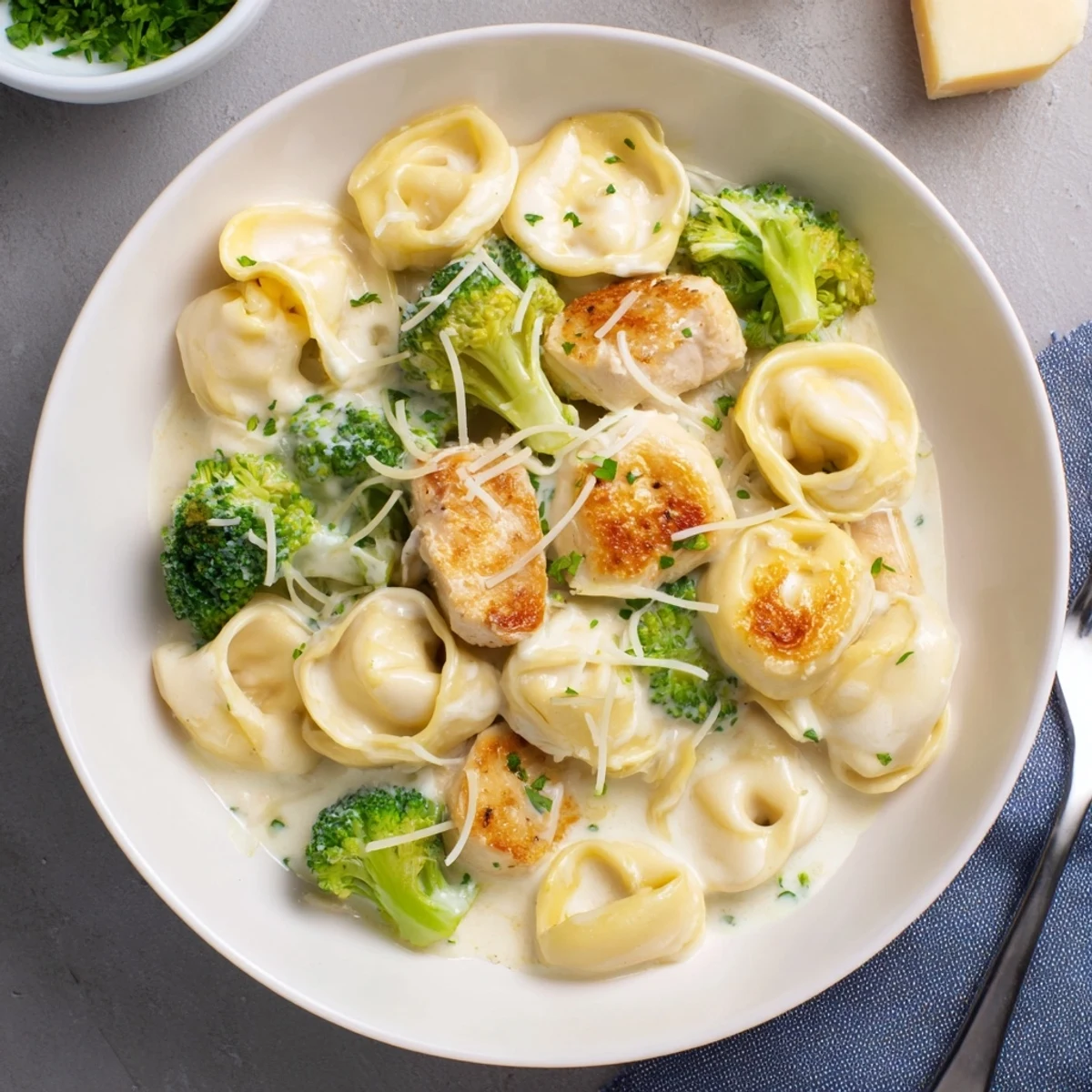 A bowl of Creamy Garlic Parmesan Tortellini Chicken Broccoli Recipe, rich, cheesy sauce