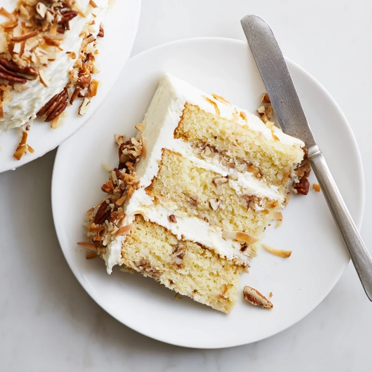 Delicious Quick Italian Cream Cake layered with coconut pecans and silky frosting on white plate