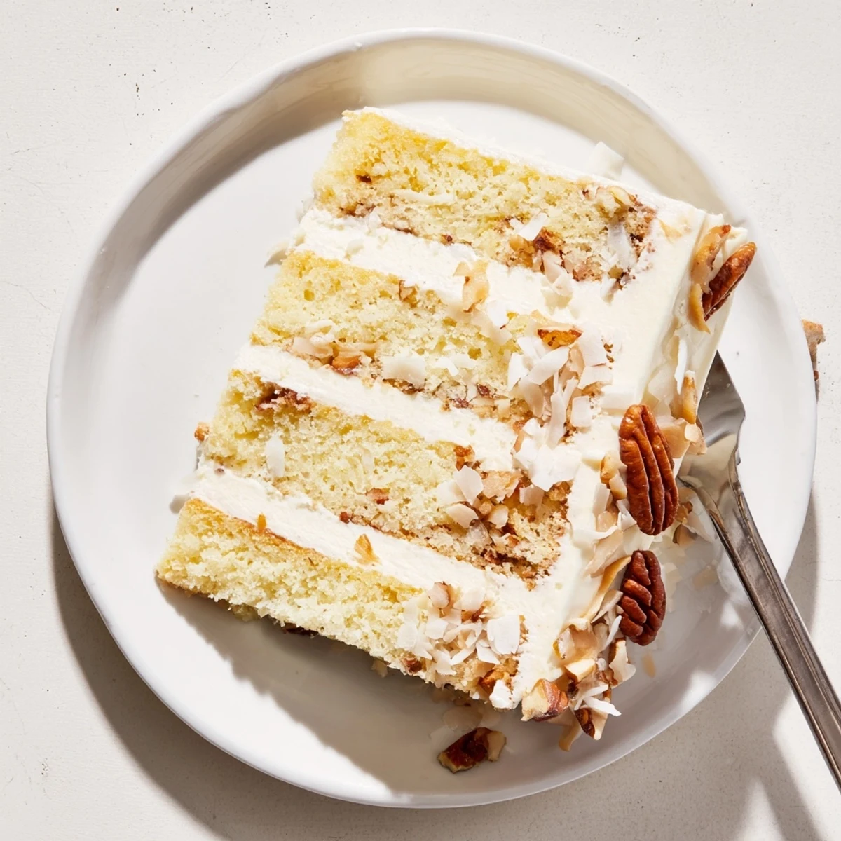 Golden Quick Italian Cream Cake topped with toasted coconut and chopped pecan pieces