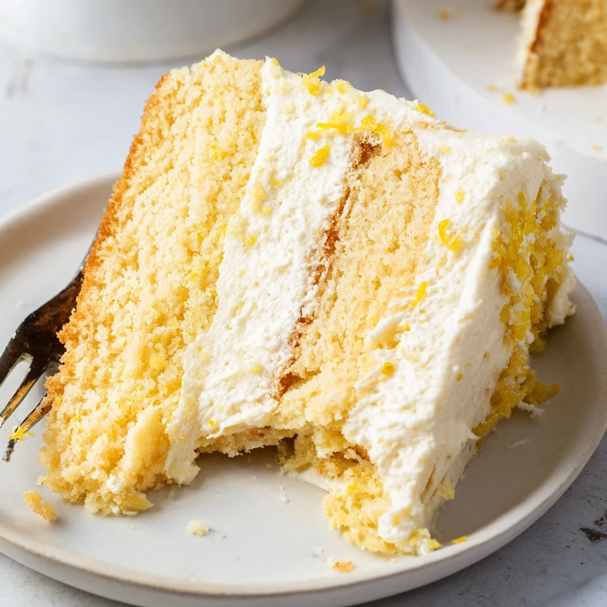 Two-layer lemon birthday cake with tangy frosting and edible flower decorations on a white stand