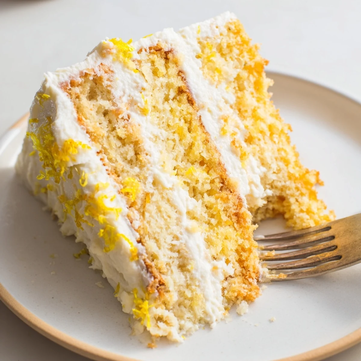 Slice of moist lemon birthday cake revealing tender yellow crumb topped with zesty cream cheese frosting