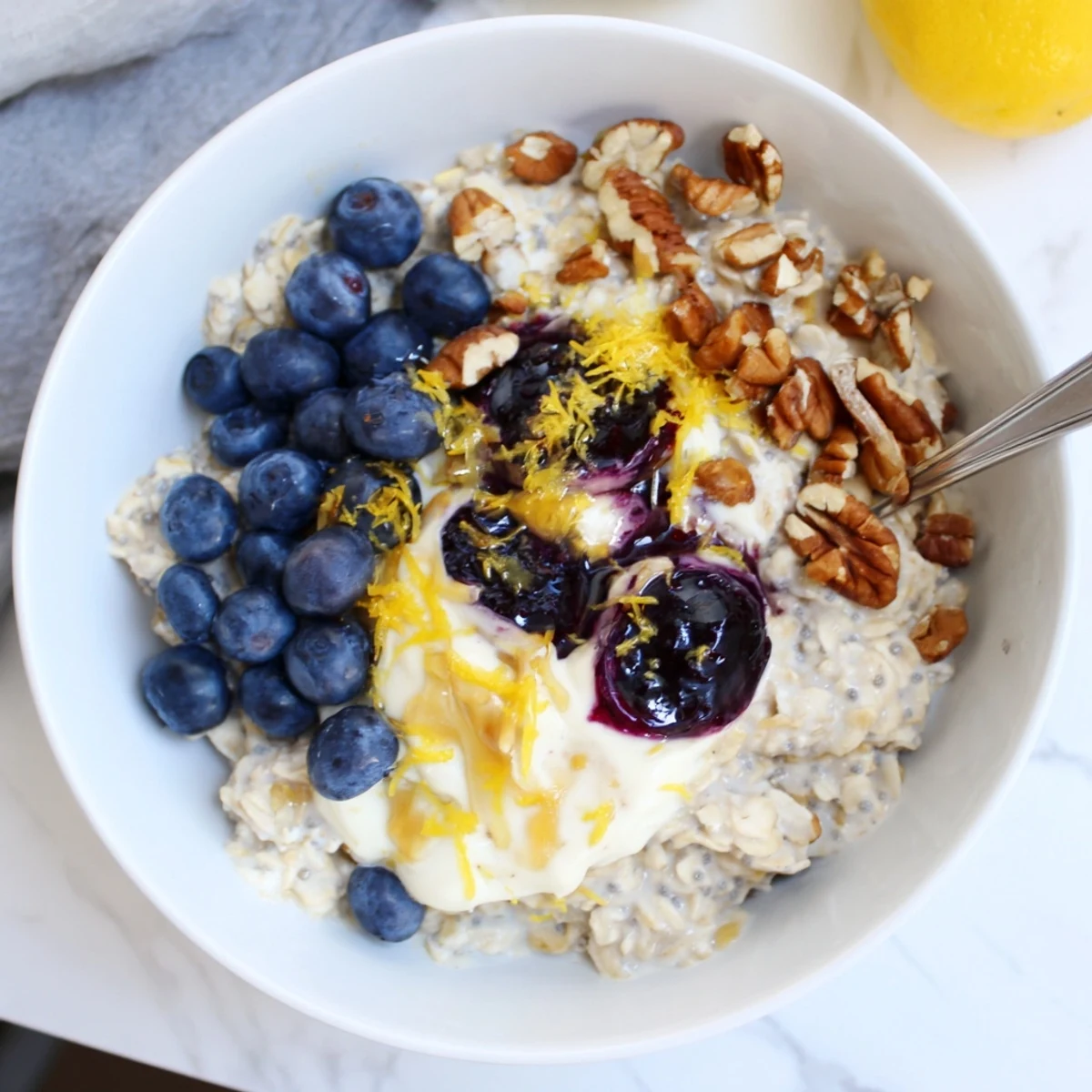 Tangy, sweet Blueberry Lemon Overnight Oats topped with chopped nuts and a spoon