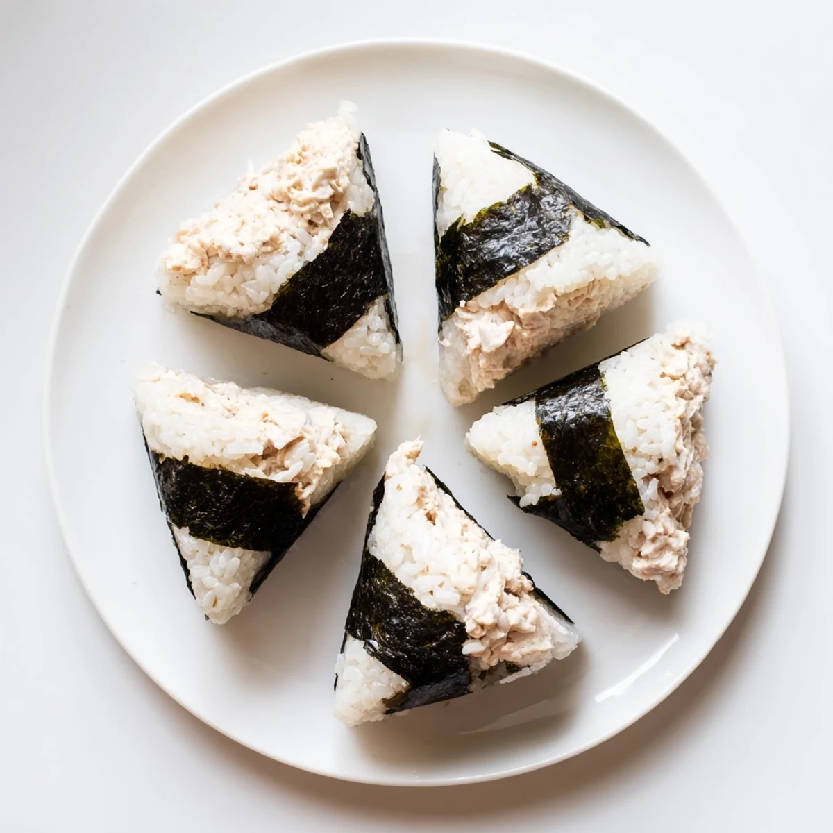 Homemade tuna mayo onigiri with nori strips arranged on wooden board