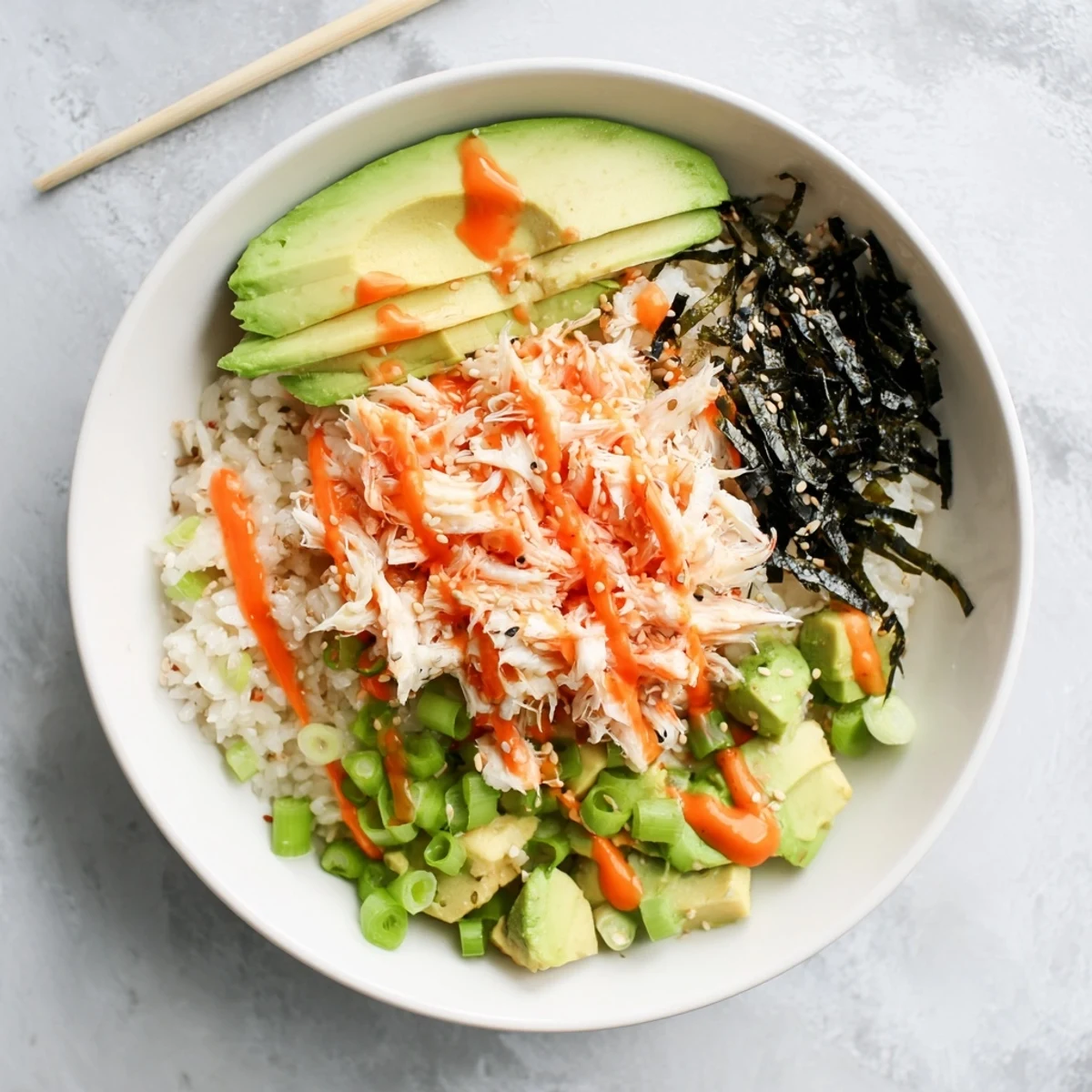 Close-up of California Roll sushi bowl featuring rice, imitation crab, avocado, nori strips, and pickled ginger