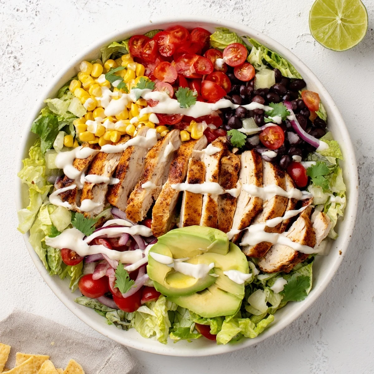 Vibrant Southwestern chicken salad plated with seasoned sliced chicken breast, cherry tomatoes, red bell pepper, and zesty lime crema dressing.