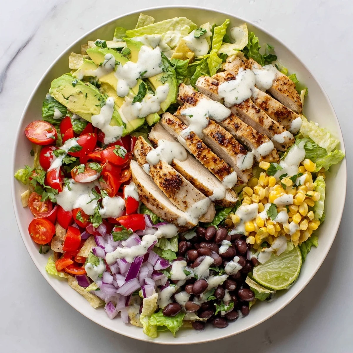 Colorful southwestern chicken salad bowl with juicy grilled spiced chicken strips atop crisp romaine lettuce, black beans, corn, and creamy avocado.