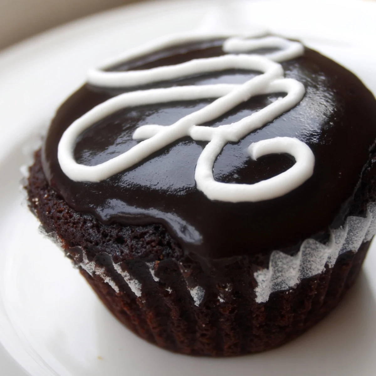 Freshly frosted Homemade Hostess Cupcakes topped with dark ganache and classic white icing swirls