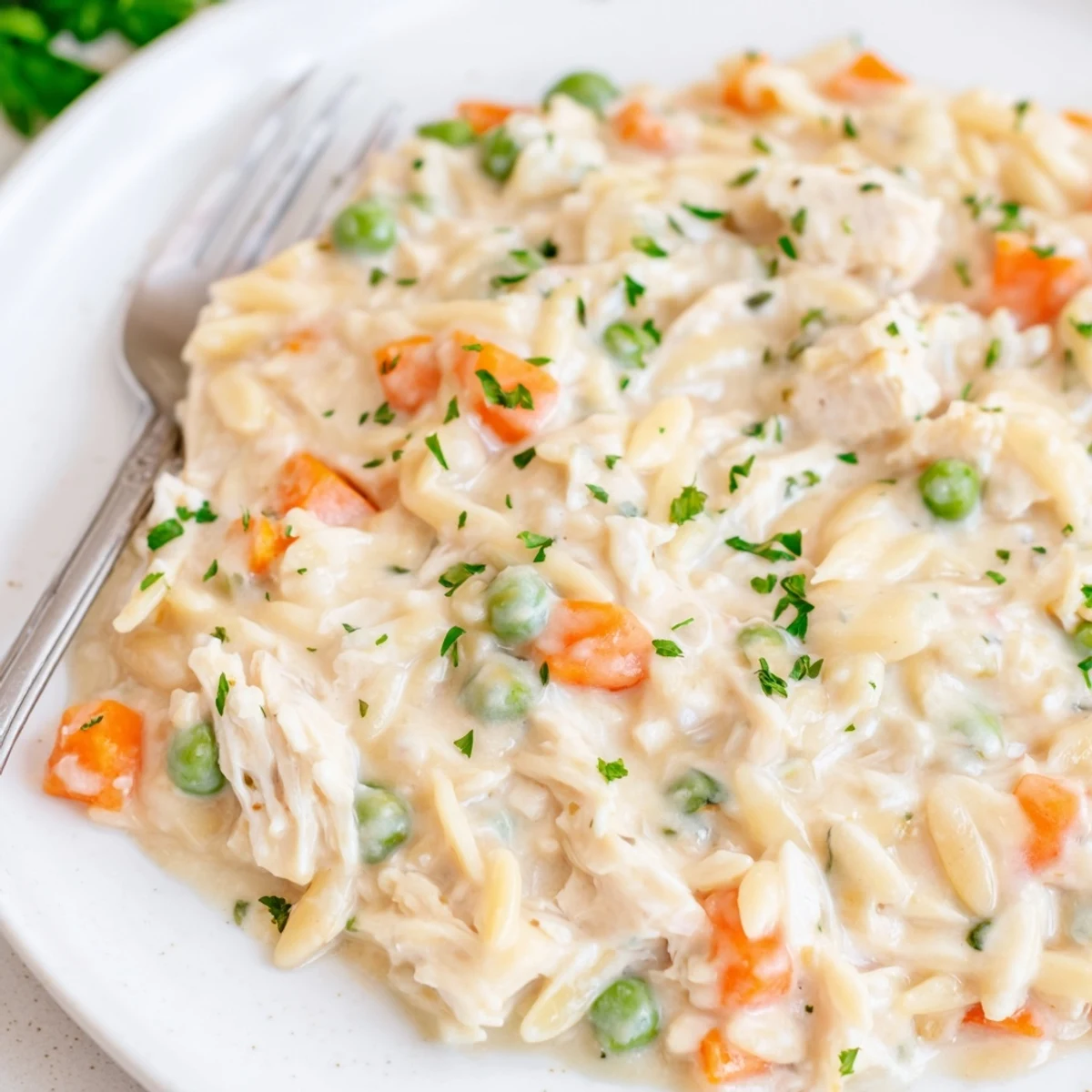 Thick and creamy chicken pot pie orzo garnished with herbs in a white skillet.