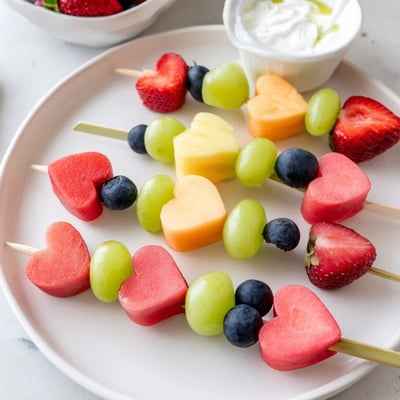 A close-up of Sweetheart Fruit Skewers with Yogurt Dip, highlighting ripe pineapple chunks and a creamy honey-drizzled dip.
