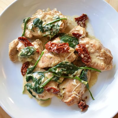 Tender Creamy Garlic Chicken with Spinach and Sundried Tomatoes served hot over steamed rice for a weeknight dinner.  